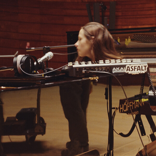 Detail-Ausschnitt: Pianistin Hania Rani sitzt am Flügel zu sehen Kopf mit Mikrofon und Teile des Flügels 